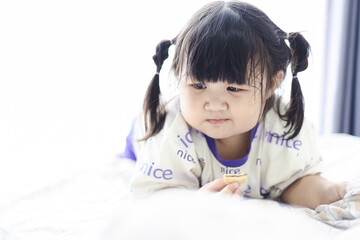 Naklejka premium What a cute little girl! Asia is happily lying on the bed and eating cookies,Beautiful young woman with tasty cookies lying on bed at home