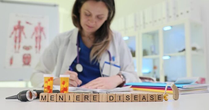 Wooden blocks spell phrase Meniere Disease near pills bottles and otoscope. Woman doctor writes notes carefully monitoring chronic inner ear disorder
