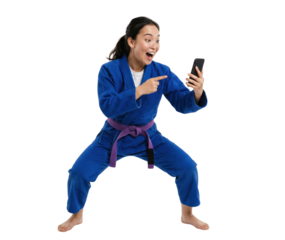 Excited young woman in blue martial arts uniform using smartphone isolated