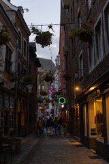 Fototapeta premium Aachen, North Rhine-Westphalia , Germany, August 23rd, 2025, Charming city alley with lively nighttime illumination, Stroll through lively historic town illuminated by colorful