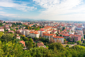 Fototapeta premium Bergamo panoramic city view with red rooftops and green hills above a busy town