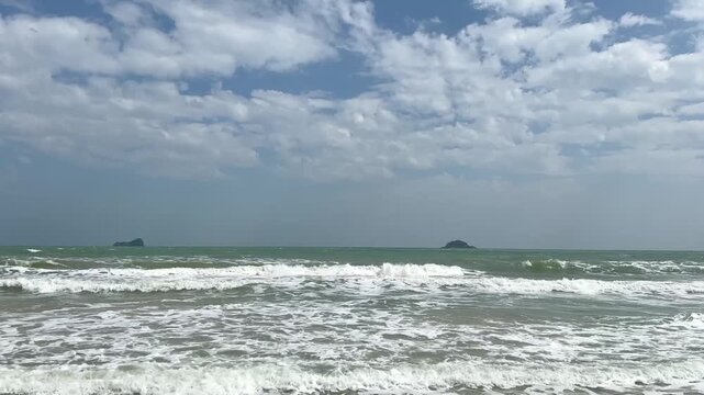 video of wind blowing ocean waves during daytime with scattered clouds and active sea surface creating a fresh coastal mood.
