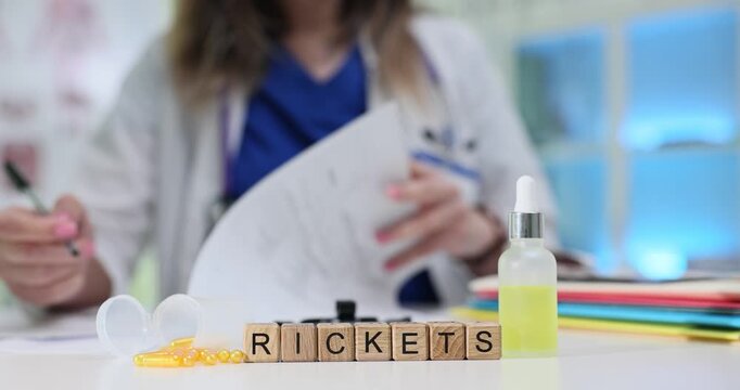 Woman physician documents recommendations for bone health. Miniature wooden cubes form word Rickets near tablets and container of liquid medicine