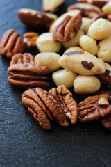 Assorted nuts mix with pecans and macadamia on dark background. Healthy snack concept, natural plant protein, clean eating and gourmet food photography