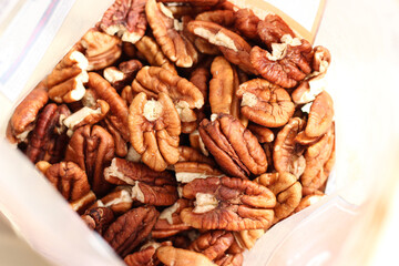 Pecan nuts inside opened bag, top view. Natural wholesome snack, rich nut texture, organic food ingredient, healthy eating and plant-based nutrition concept