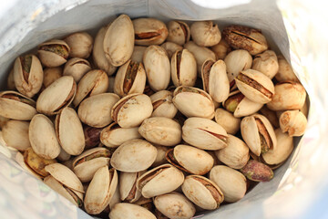 Pistachio nuts in shell inside opened bag. Healthy snack concept, salted nuts texture, natural food background, close-up food photography