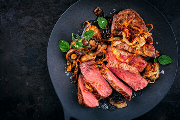 Zwiebelrostbraten roast beef - sirloin beef steak braised with fried onion rings and mushrooms served as top view on a design plate 
