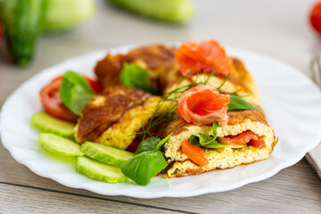Juicy omelet with salmon pieces and aromatic herbs