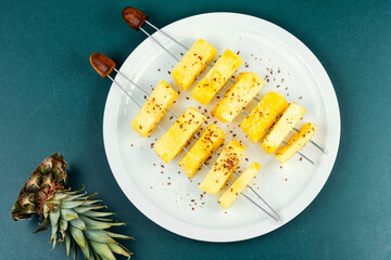 A plate pineapple skewers with sesame seeds.