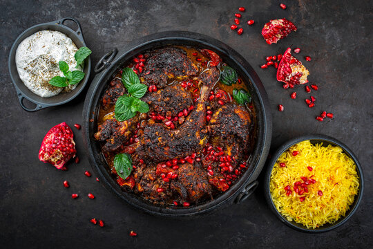 Traditional authentic Persian khoresh fesenjan - chicken stew with walnuts and pomegranate sauce, saffron basmati rice and mast o khiar - mint yogurt dip