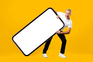A man stands with a large empty sign in front of a bright yellow background. He smiles while holding the sign at an angle, creating a playful scene.