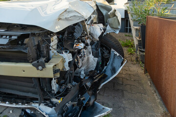 Severely damaged white car after collision, crumpled hood and exposed engine bay, structural deformation and mechanical exposure, accident scene, broken bumper and fender, safety and insurance concept