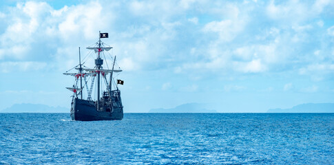large black pirate ship sailing on ocean, Jolly Roger flag fantasy adventure sea travel, historical galleon vessel, open water horizon, childhood fantasy dream, cultural heritage pioneering spirit © kittyfly