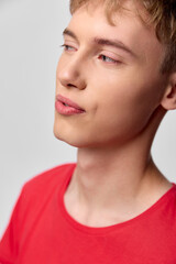 Fototapeta premium Young man, thoughtful profile, closeup of face in a red shirt, calm gaze and soft lighting, minimal background, expressive mood, studio vibe and natural skin tone emphasis
