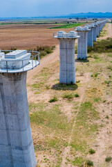 The concrete pillars/piers for the high-speed rail track are under construction at the unfinished construction site.