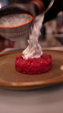 close-up of a plate with meat tartare on which a cheese manteca is placed, it is soft and stringy.