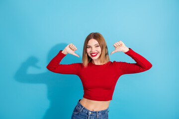 Cheerful young woman in casual red top smiling against a vibrant blue background