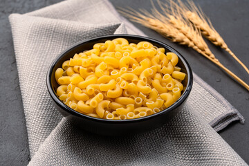 Raw macaroni pasta on black stone background