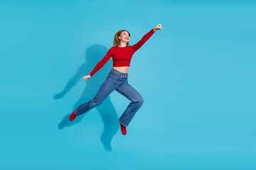 Obraz premium Charming young woman dressed in vibrant attire poses confidently on a stylish blue background exuding happiness and joy
