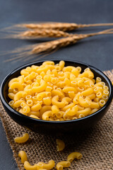 Raw macaroni pasta on black stone background
