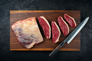 Raw dry aged wagyu Brazilian picanha steaks from the sirloin cap of rump beef sliced and served on wooden cutting board with knife 