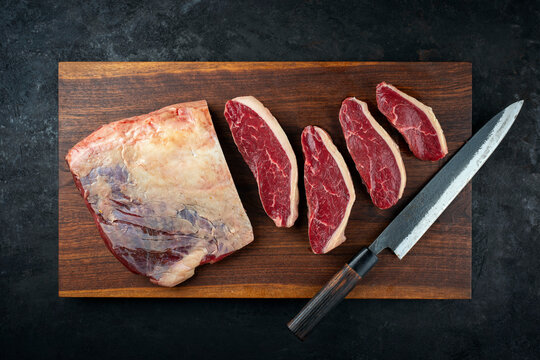Raw dry aged wagyu Brazilian picanha steaks from the sirloin cap of rump beef sliced and served on wooden cutting board with knife 
