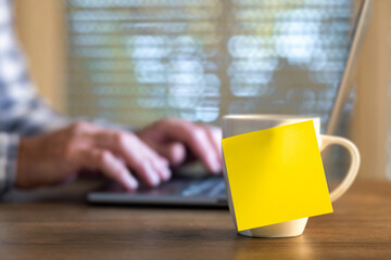 Yellow sticky note on mug office desk