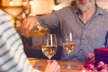 Cropped shot of a happy couple pouring wine into glasses during romantic date for cheering toasting clinking celebration of special event, Christmas, anniversary, engagement, Valentine`s Day