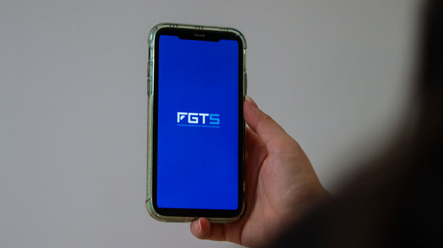Celular com aplicativo FGTS aberto na tela, representando acesso digital a direitos trabalhistas, servi&ccedil;os financeiros e benef&iacute;cios sociais no Brasil. S&atilde;o Paulo SP em 14 dez 25