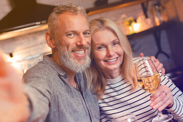 Happy married couple taking selfie while on a romantic date in the kitchen. Husband and wife, spouses, girlfriend and boyfriend streaming online on anniversary Valentine`s Day