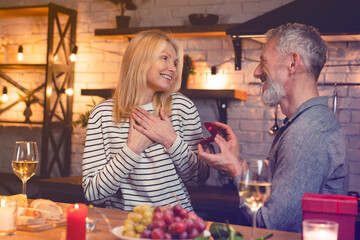 Mature caucasian man proposing his girlfriend during romantic date in the kitchen. Marriage, engagement, ring for wedding. Present gift on Valentine`s Day