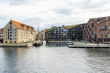 Copenhagen, Denmark - 30 September 2025: View of tranquil waters reflecting historic brick buildings and modern architecture under a cloudy sky.