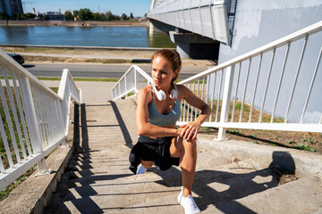Female athlete doing warm-up stretching exercise on urban steps outdoors.