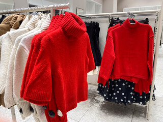 Red and white sweaters on display rack in clothing store