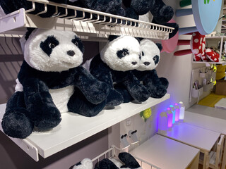 Shelves displaying plush panda toys in toy store with colorful decor