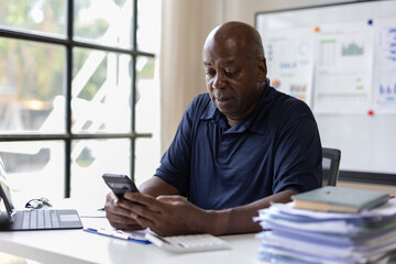 Senior accountant using smartphone in office, financial analysis and mobile technology.