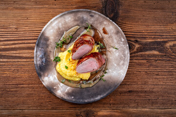 Pork fillet roast wrapped in prosciutto ham bacon with polenta and fresh herbs served as top view on a rustic design plate