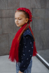  Portrait of smiling 7 years old girl with eye-catching red synthetic braids arranged in decorative...