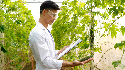 man scientist wearing white medical gown analyzing quality of vegetable and plant and then writing results in document on clipboard