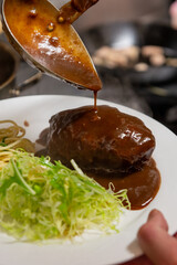 デミグラスソースをかけるハンバーグのクローズアップ