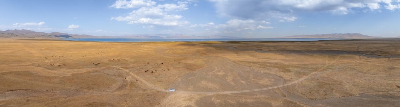 Road and off-road vehicle, Aerial view, Vast empty landscape at the mountain lake Song Kul in autumn, Moldo Too Mountains, Naryn region, Kyrgyzstan