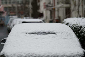 A close-up shot of a car heavily covered in fresh, wet snow on a winter day.
