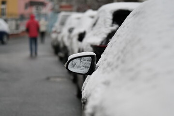 A close-up shot of a car heavily covered in fresh, wet snow on a winter day.