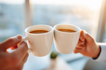 Cheers with coffee cups in warm sunlight