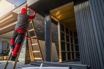 Worker Uses Ladder to Fix Building Exterior in the City