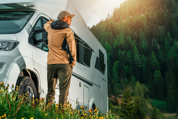 Man Stands Next to Campervan in Nature Landscape © Tomasz Zajda