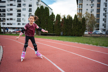 Obraz premium Girl rollerblading on running track wearing protective gear