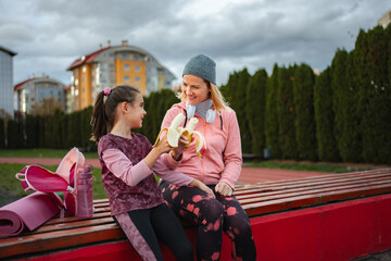 Mother and daughter sharing banana after outdoor workout