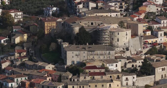 Aerial view of Gesualdo Castle, stone buildings with red-tiled roofs present a contrast against the green trees, Gesualdo, Campania, Italy.