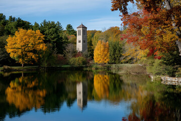 Obraz premium This stunning autumn landscape features vibrant fall foliage reflected in a serene lake, encapsulating the beauty of nature and evoking feelings of reflection and peace.